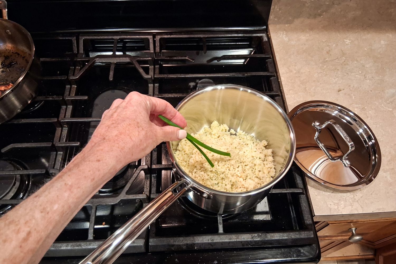 A person stirs rice in the Cuisinart MultiClad Pro 12 Piece Stainless Cookware Set pot