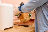 A person removes a loaf of bread from the Amazon Basics 2-Pound Nonstick Bread Making Machine