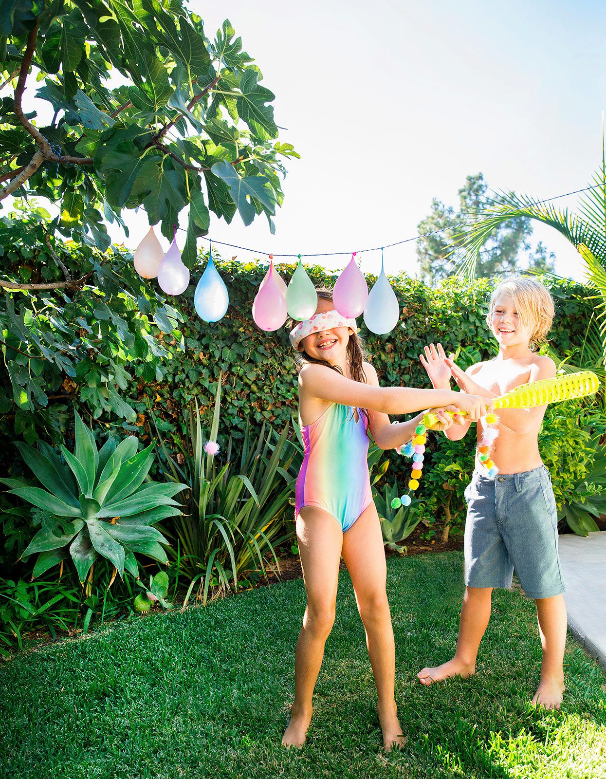 blindfolded girl swinging bat at hung water balloons