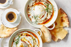 Poached eggs served in bowls with bread and a cup of coffee on the side
