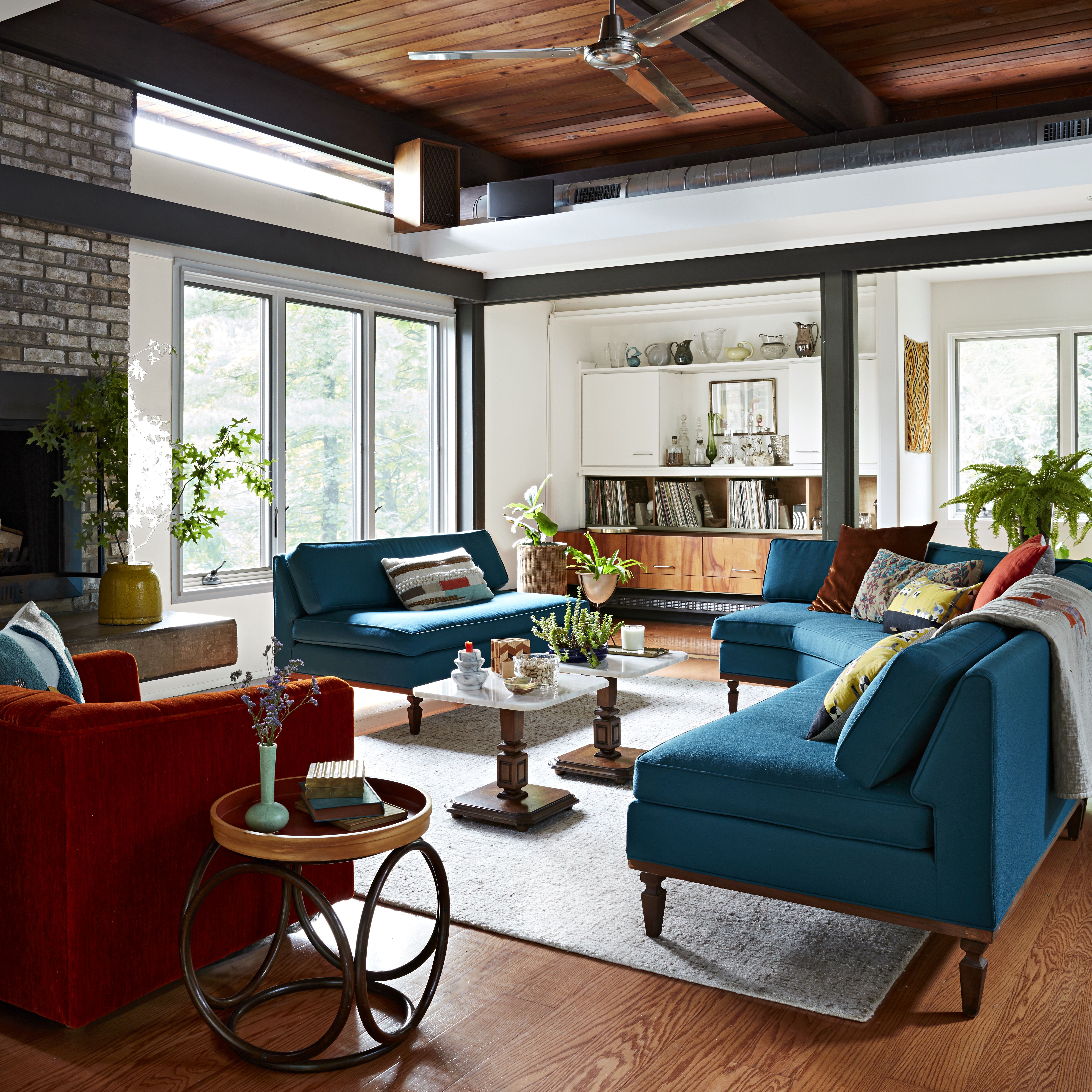 BHG Adoff House Story - mid century modern living room with stone fireplace and burnt orange and teal sofas and chairs