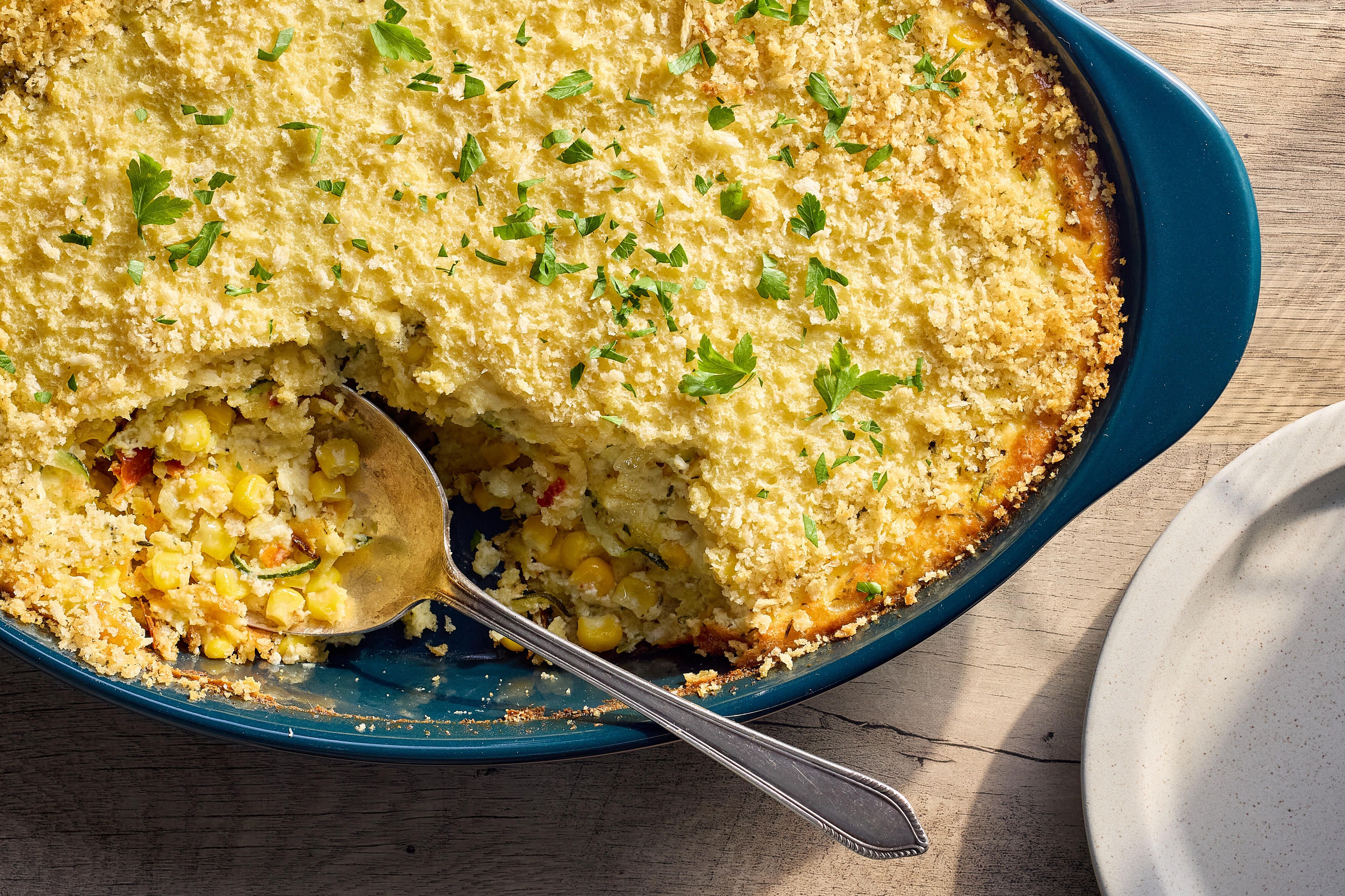 A baked corn pudding casserole in a dish with a spoon