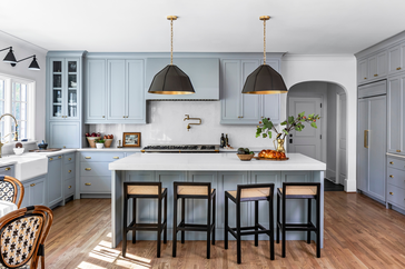 blue kitchen with black pendants and black bar stools