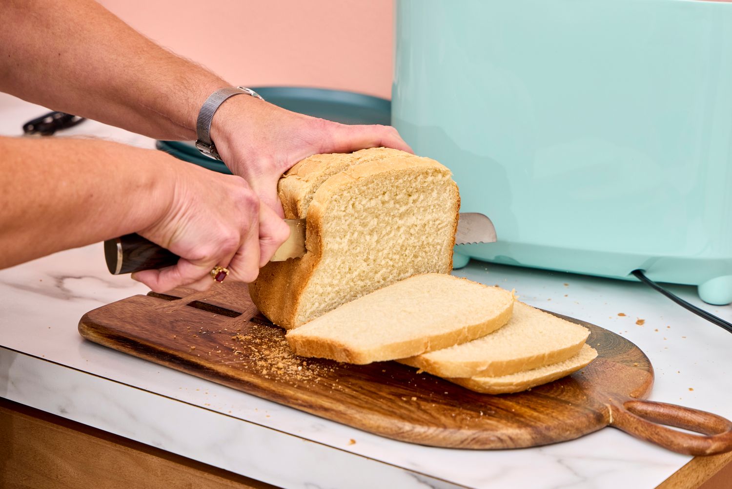 A person slices bread made in the Elite Gourmet Programmable Bread Maker