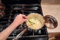 A person stirs rice in the Cuisinart MultiClad Pro 12 Piece Stainless Cookware Set pot