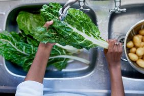 person washing swiss chard in sink