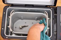 A person wipes down the inside of the Zojirushi Home Bakery Virtuoso Plus Bread Maker