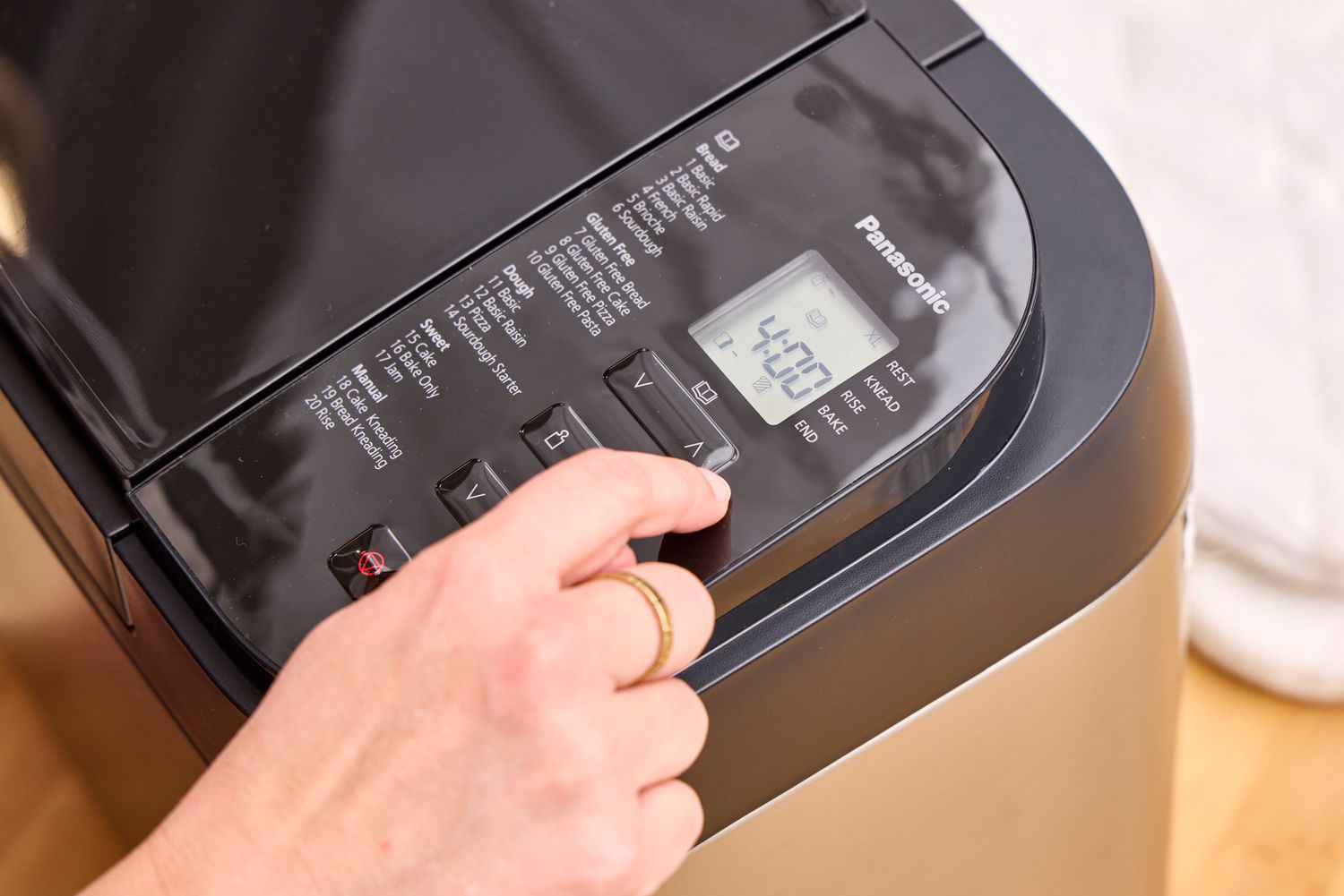 A person presses a button on the Panasonic SD-R2550 Automatic Bread Maker