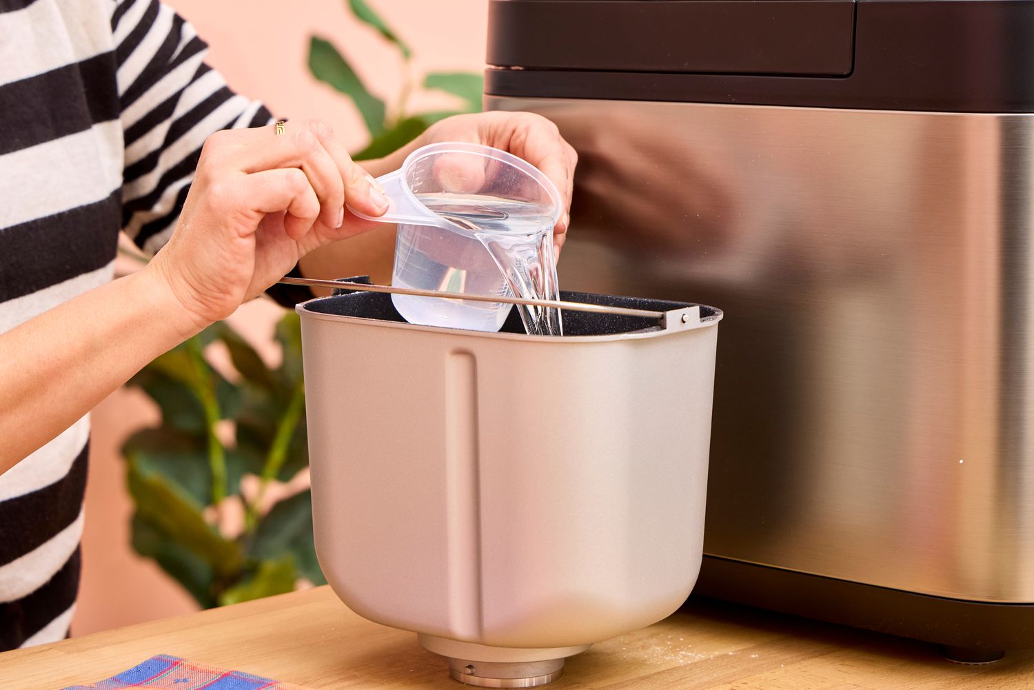 A person pours water into the Panasonic SD-R2550 Automatic Bread Maker