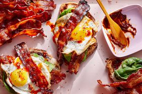 Open-faced breakfast sandwiches with toast, lettuce, bacon, and eggs.