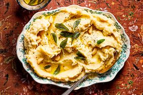 A dish of mashed potatoes garnished with herbs and served on a patterned plate