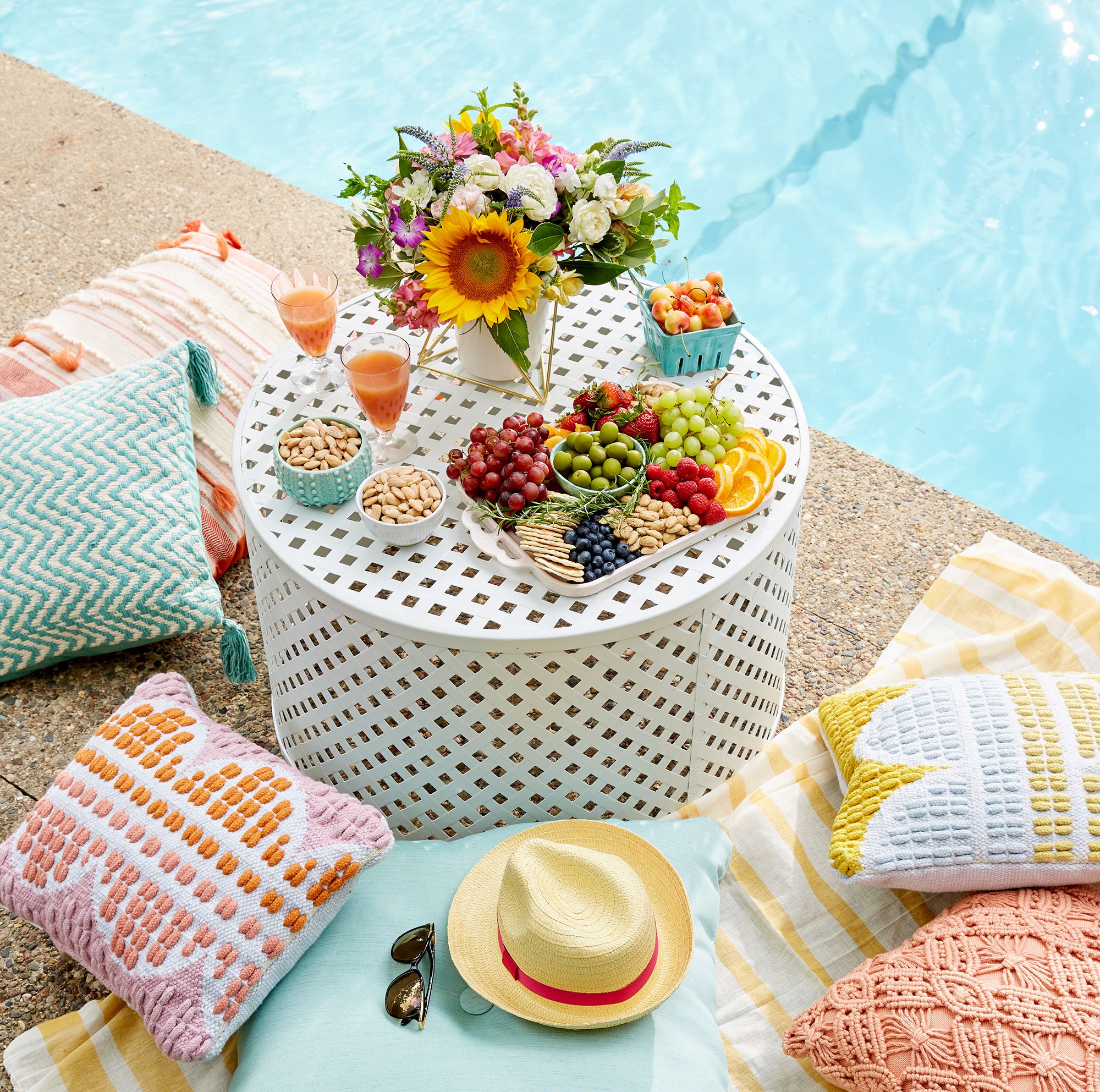 white poolside table with snacks hat sunglasses