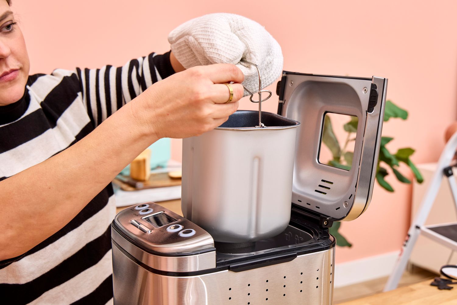 A person removes the load pan from the Cuisinart CBK-110 Compact Automatic Bread Maker