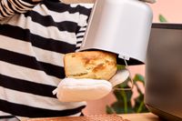 A person removes a loaf of bread from the Panasonic SD-R2550 Automatic Bread Maker