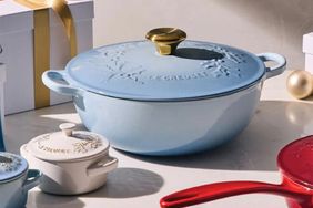Le Creuset cookware displayed on a surface with a holiday theme and packaging in the background