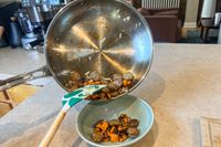 A person pours cooked sausage and carrots from the Viking Culinary 3-Ply Stainless Steel Cookware Set pan into a bowl