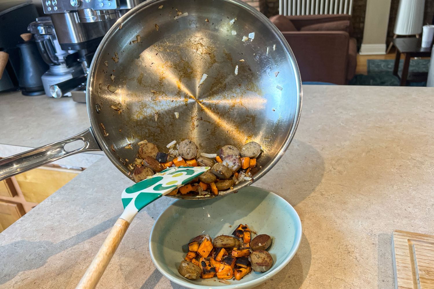 A person pours cooked sausage and carrots from the Viking Culinary 3-Ply Stainless Steel Cookware Set pan into a bowl