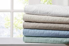 lifestyle image of stack of comforters by window