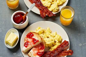 Plate with scrambled eggs, toast with jam, bacon