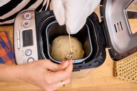A person removes a loaf of bread from the Cuisinart CBK-110 Compact Automatic Bread Maker