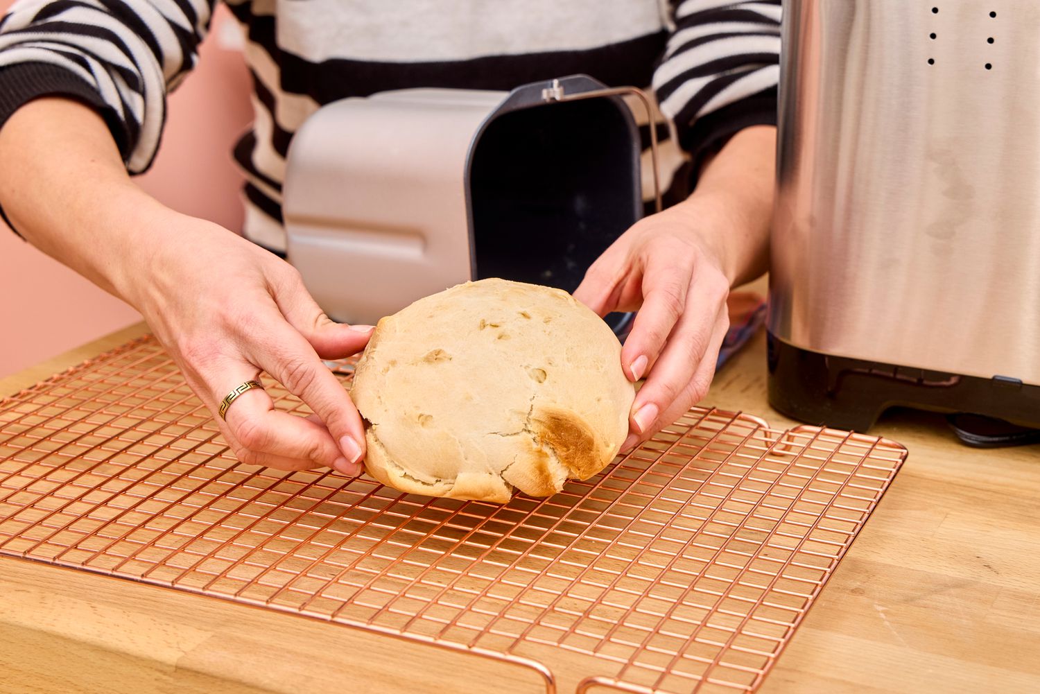 A person removes a loaf of bread from the Cuisinart CBK-110 Compact Automatic Bread Maker