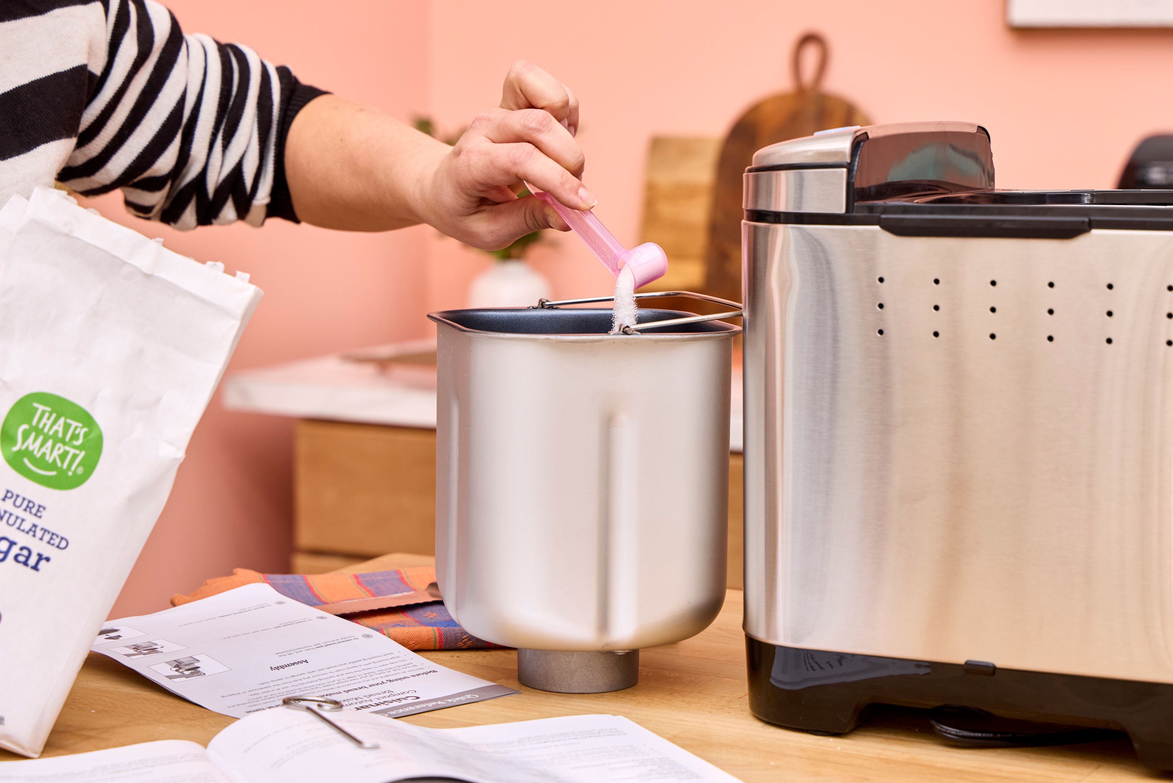 A person pours sugar into the Cuisinart CBK-110 Compact Automatic Bread Maker