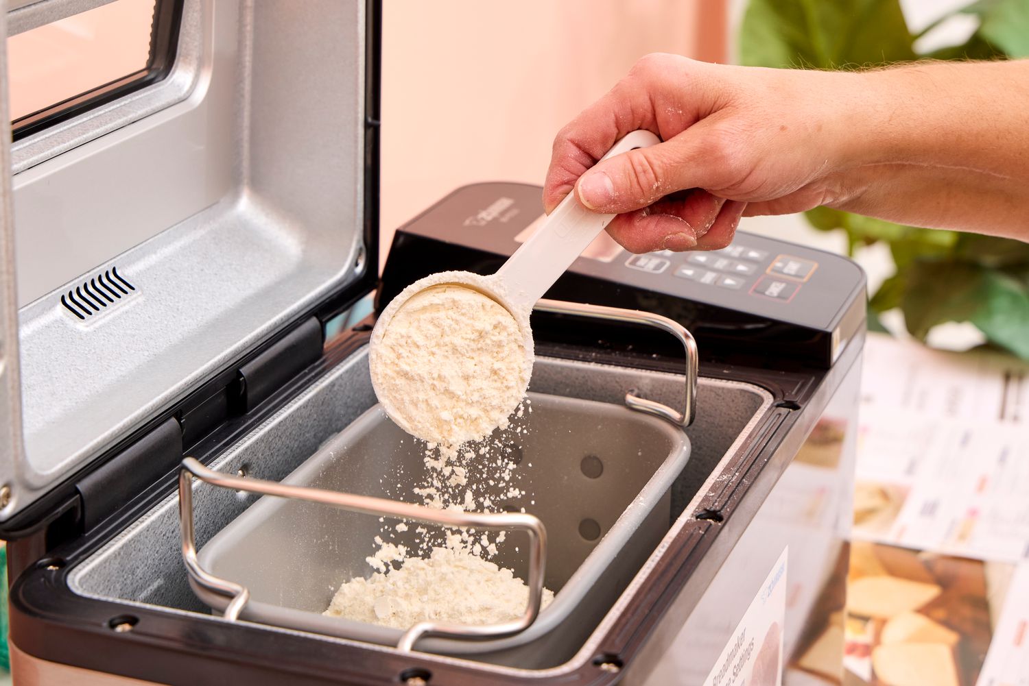 A person pours flour into the Zojirushi Home Bakery Virtuoso Plus Bread Maker