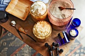 A table with bowls containing scrub mixtures, essential oil bottles, and utensils, forming a DIY skincare station