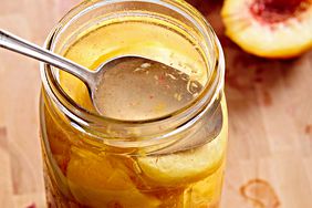 Packing canned peaches into jars spoon wooden table
